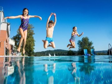 Děti ve venkovním bazénu u pláže s výhledem na Máchovo jezero
